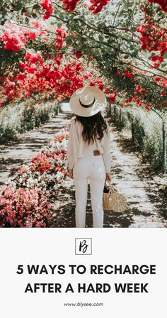 a woman standing in front of red flowers wearing a white suit and hat with her back to the camera