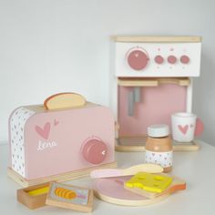 a pink toaster sitting on top of a table next to other kitchen accessories and utensils