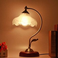 a lamp that is sitting on top of a table next to books and a vase