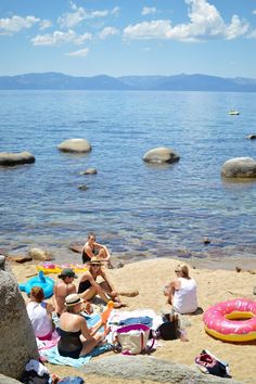 some people are sitting on the beach by the water