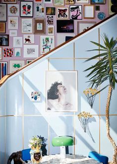 a dining room table with blue chairs and pictures on the wall behind it in front of a staircase