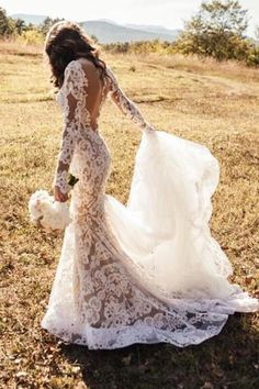 a woman in a wedding dress is walking through the grass