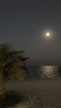 the moon is setting over the ocean and beach