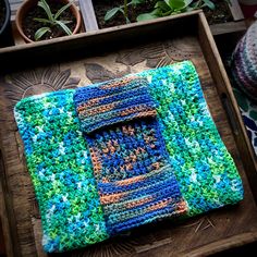 a crocheted blanket sitting on top of a wooden table next to potted plants