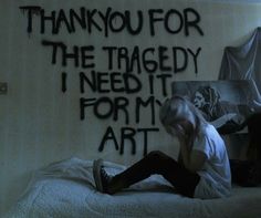 a woman sitting on top of a bed in front of a wall with words written on it