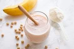 there is a banana and milk in the glass on the table next to some cereal