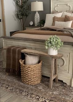 a white bed sitting next to a wooden table with a potted plant on top of it