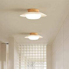 two circular lights are hanging from the ceiling above a sink in a bathroom with white walls and flooring