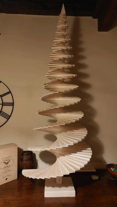 a christmas tree made out of wooden planks on a table next to a clock