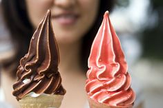 a woman holding two ice cream cones in her hands