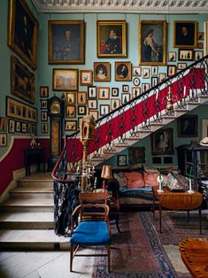 a living room filled with furniture and pictures on the wall above it's stairs