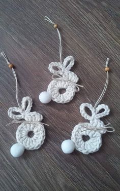 three crocheted ornaments hanging from strings on a wooden table with string and beads