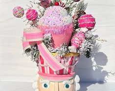 a pink vase filled with lots of different types of decorations on top of a table