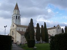 an old church with trees and benches in front