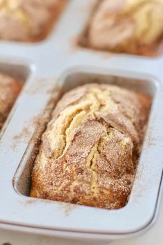 a muffin in a pan with some powdered sugar on top and other muffins behind it