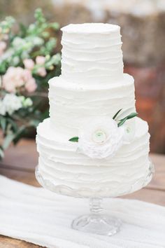 a white wedding cake sitting on top of a wooden table