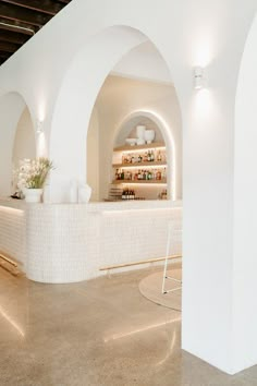 the interior of a restaurant with white walls and arches on the ceiling, along with an open bar