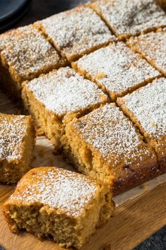 a wooden cutting board topped with slices of cake and powdered sugar on top of it