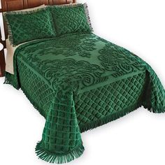 a green bedspread with tassels on the headboard and foot board