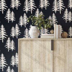 a wallpaper with white trees on it in a black and white color scheme is the focal point for this room