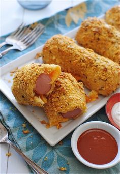 two pieces of breaded chicken on a plate with dipping sauces next to it