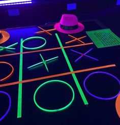 an illuminated neon tic - tac - toe game with hats on the table