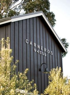 a black building with the name carneros on it's side in front of some trees