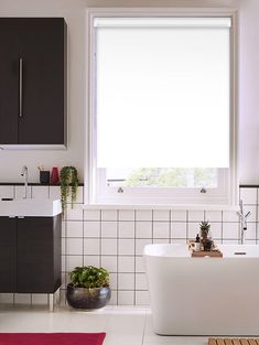 a white bath tub sitting under a window next to a sink