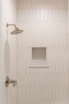 a bathroom with white hexagonal tiles and a shower head