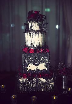 a three tiered wedding cake with red roses on the top and black icing