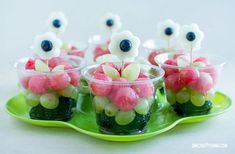 small cups filled with candy and flowers on top of a green platter that is sitting on a table