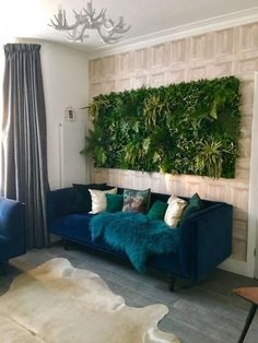 a living room with blue couches and green plants on the wall behind it,