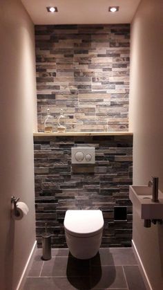 a bathroom with a toilet and stone wall