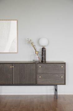 a sideboard with two vases on top of it and a painting behind it