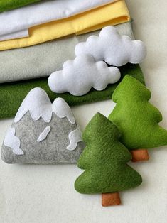 four felt trees are sitting next to each other on the ground, and one is green with white clouds