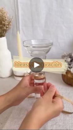 a person is holding a glass jar with some flowers in it on a white table