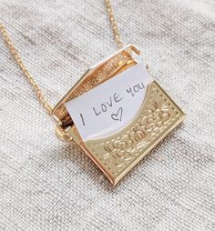 a piece of paper that says i love you is attached to a gold plated necklace