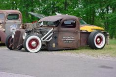 two old trucks parked next to each other on the side of the road with trees in the background