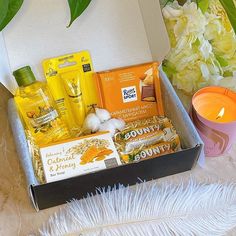 an open box filled with personal care items next to a candle and some flowers on a table