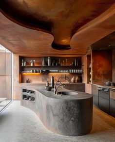 a large kitchen with an unusual sink and countertop area in the center, surrounded by shelves filled with pots and pans