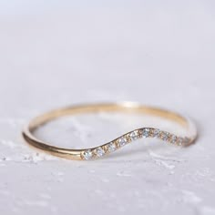 a yellow gold wedding band with diamonds on it's side, sitting on a white surface