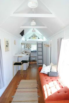 a living room filled with furniture and a ladder leading to the top floor in front of a kitchen