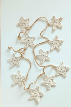 small crocheted stars are hanging from a string on a white tablecloth background