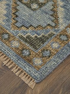 a blue and brown area rug with fringes on the floor next to a wood floor