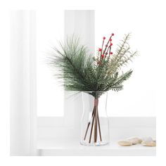 a vase filled with red berries and greenery on top of a white counter next to a window