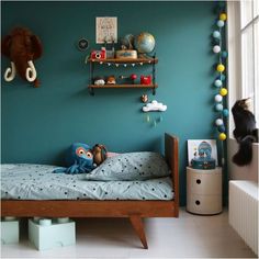 a child's bedroom with blue walls and toys on the shelves above the bed