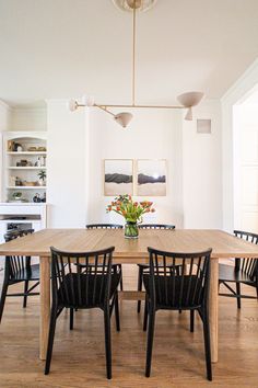 a dining room table with four chairs and a vase on the table in front of it