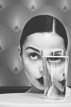 a woman holding a glass with water in front of her face