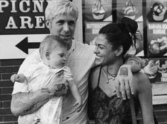 a man and woman holding a baby in front of a store