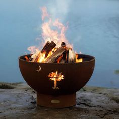 a fire pit sitting on top of a sandy beach next to a body of water